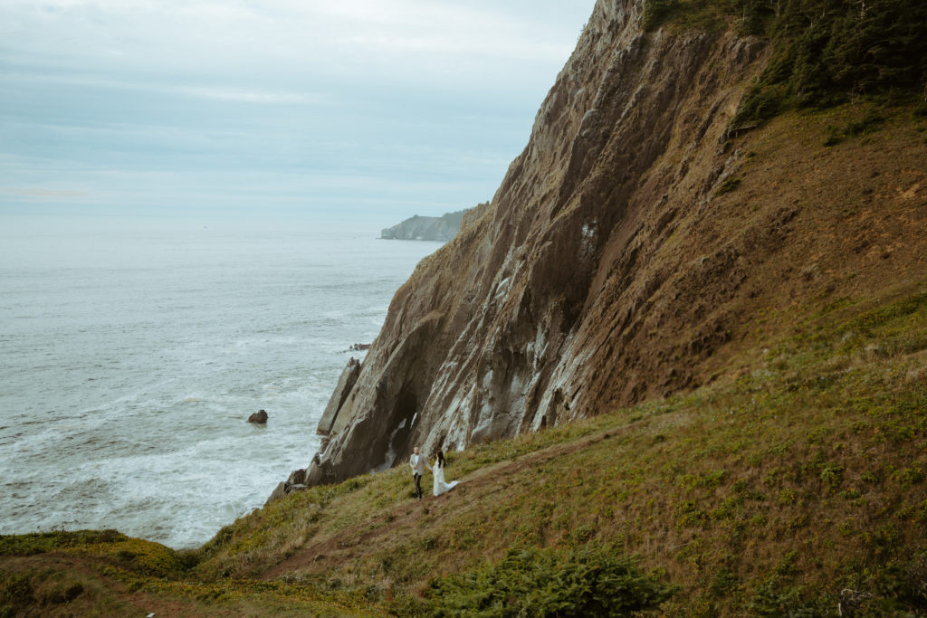 Couple walking down a mountain with an ocean view on the left